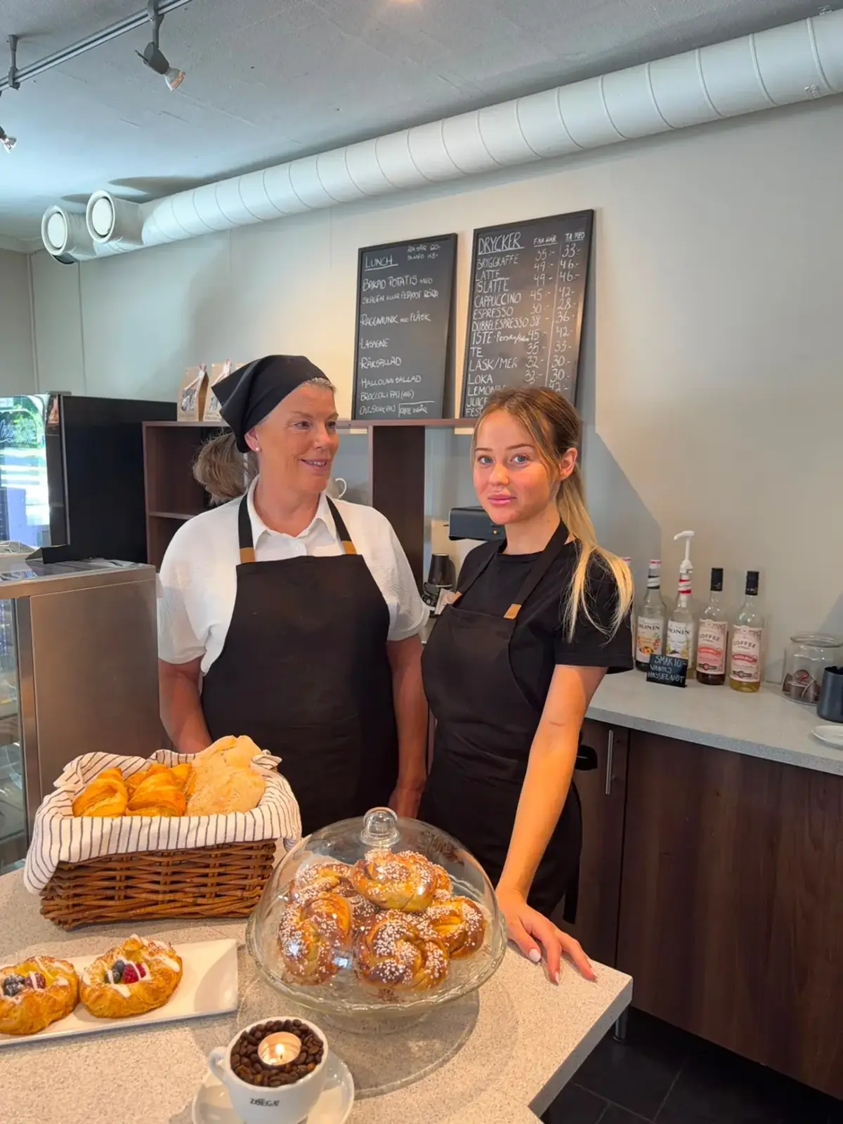 Personal i Café Källaren bakom disken med nybakade bullar, wienerbröd och kanelkransar