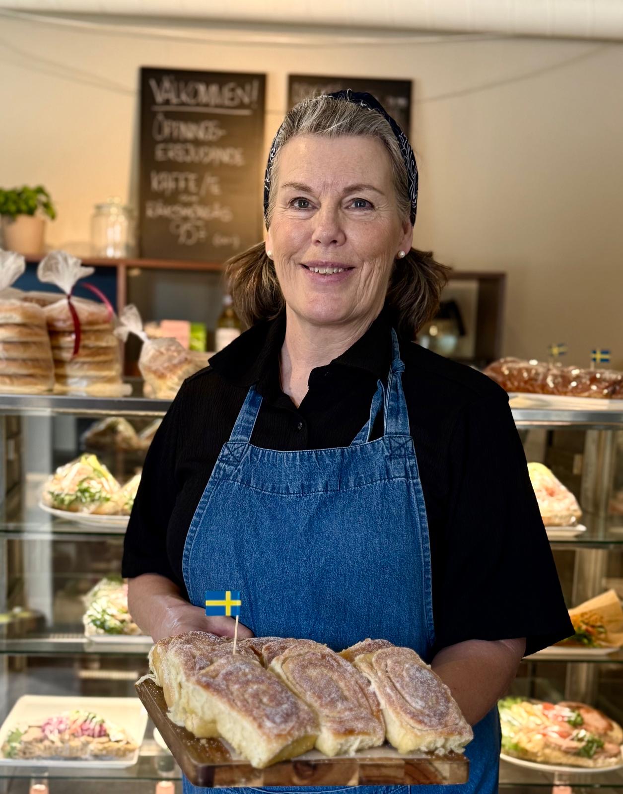 Bagare med nybakad kanelbulleplåt i caféet