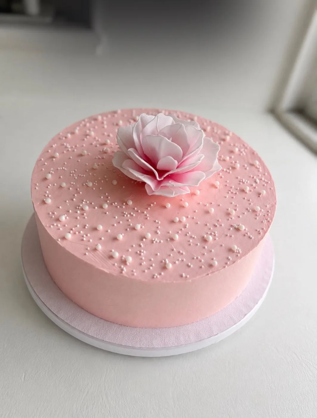 Rosa tårta med sockerblomma och pärlor